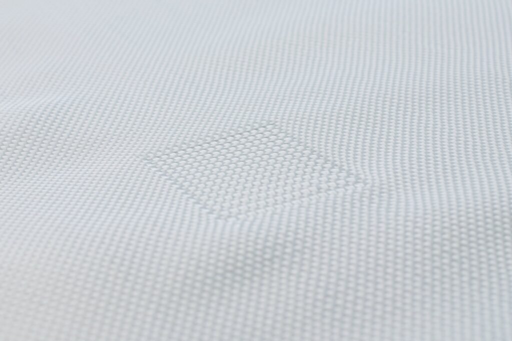 Close-up view of a geotextile mattress showing its textured surface made of synthetic fibers. The woven fabric displays a subtle pattern, emphasizing the material's strength and durability important for civil engineering applications. Ideal for erosion control and landscaping projects.
