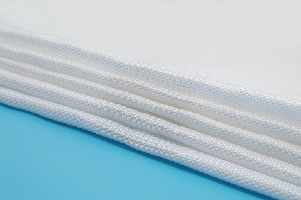 Close-up image of folded Geotextile Mattress showcasing the textured woven fabric. The material, made from synthetic fibers like polypropylene, is designed for durability and strength, evident in its layered structure and seams. Each layer represents the high-quality craftsmanship essential for effective environmental applications.